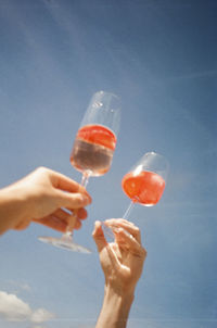 Hand holding wineglass against blue sky during summertime. shot on 35mm kodak gold 200 film.