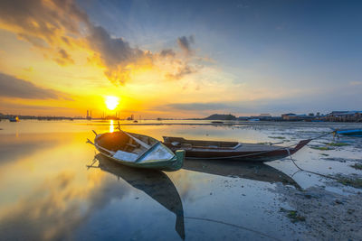 Boat moored on sea against sky during sunset