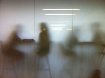 People sitting on chairs in cafe seen through glass