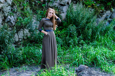 Portrait of young woman standing against plants