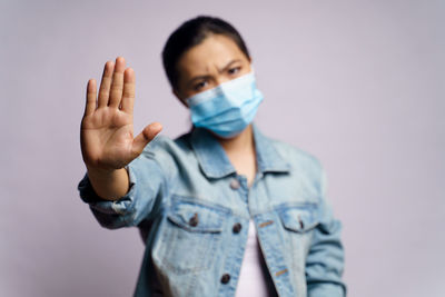 Portrait of young woman standing gesturing against gray background