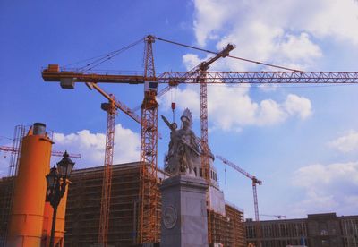 Low angle view of crane against cloudy sky