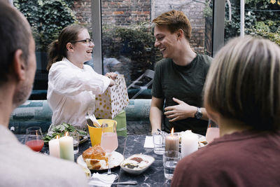 Happy woman presenting gift to brother at restaurant