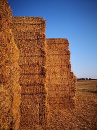 Hay bales on field against clear sky