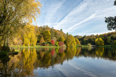 Trees by lake against sky during autumn
