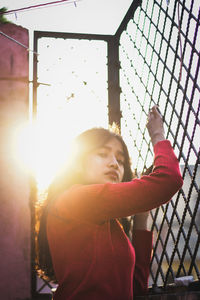 Side view portrait of young woman standing by fence