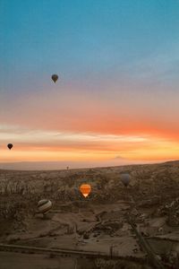 Hot air balloons flying in sky at sunset