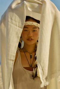 Portrait of young woman standing against curtain