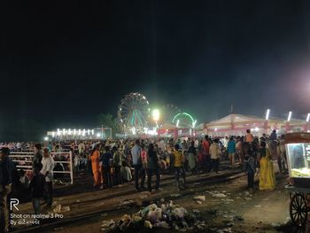 People at amusement park against sky at night