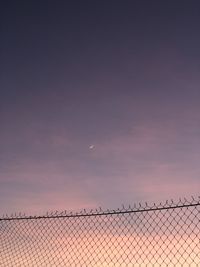 Chainlink fence against sky at sunset