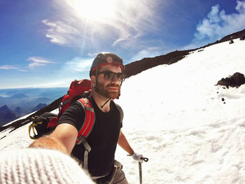 Man wearing sunglasses skiing on snow against sky during winter