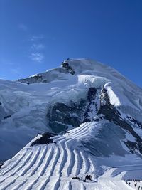 Aerial view of snowcapped mountain against blue sky