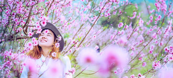 Portrait of young woman standing amidst flowering plants
