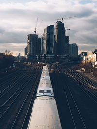 High aangle view of railroad tracks amidst buildings in city against sky