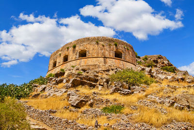 Low angle view of old ruin building against cloudy sky