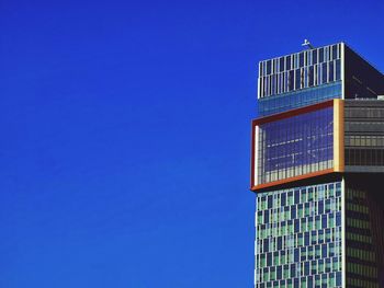 Low angle view of modern building against clear blue sky