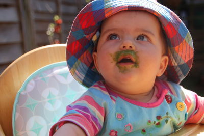 Close-up of cute baby girl with messy food looking away outdoors