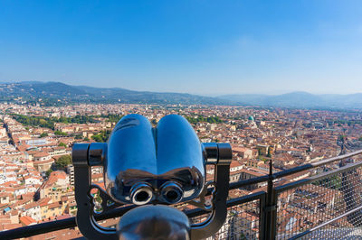 Coin-operated binoculars on cityscape against blue sky in city