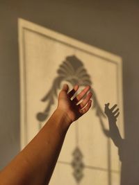 Cropped hand of woman gesturing against wall