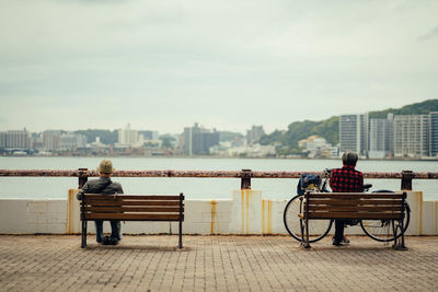 Rear view of man sitting on bench in city