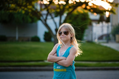 Portrait of blonde young girl crossing arms with sunglasses on