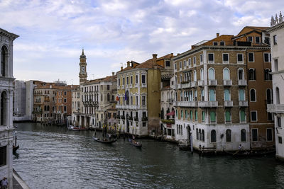 Gondolier and tourists at gondolas in grand canal with traditional venetian colorful houses