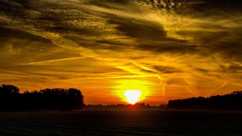 Scenic view of silhouette field against sky during sunset