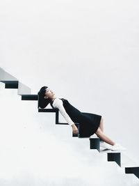 Young woman lying on steps against white background
