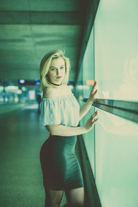 Portrait of young woman standing by window