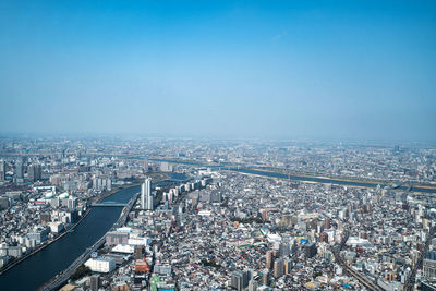 High angle view of city buildings against blue sky