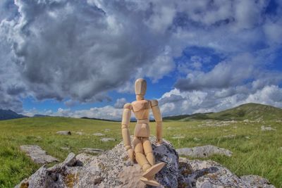 Cross on rocks by land against sky