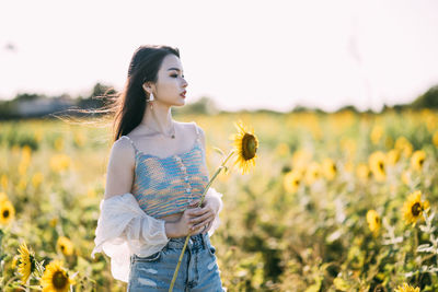 Portrait of young woman standing amidst flowers