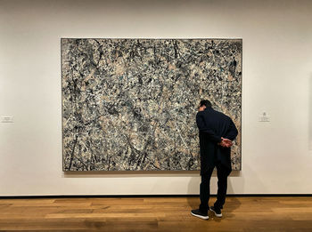 Rear view of man standing against wall at museum