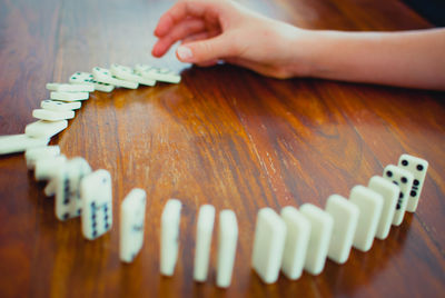 Close-up of human hand pushing first domino in a row