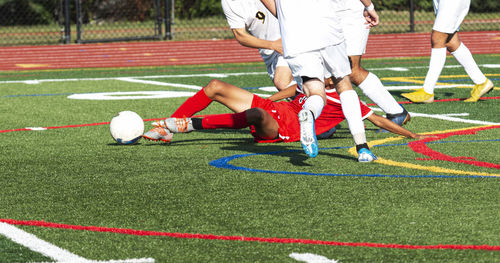 Low section of men playing soccer on field