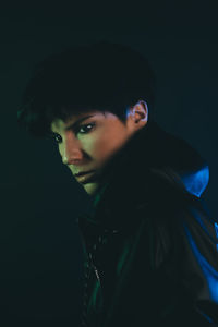 Portrait of young man against black background