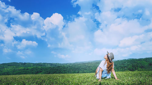 Rear view of woman standing on field against sky