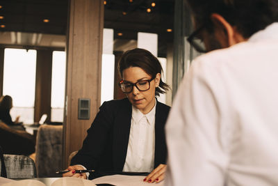 Mid adult female lawyer discussing paperwork with client at table in office