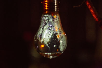 Close-up of illuminated glass hanging against black background