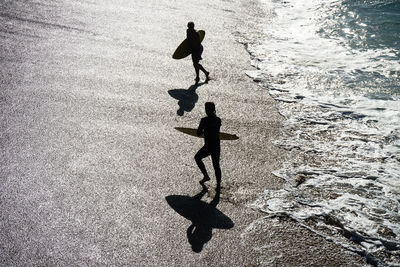 High angle view of silhouette people on sea shore