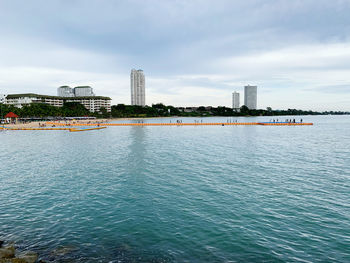 Sea by buildings against sky in city
