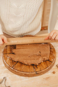 Girl's hands rolls out ginger dough with a rolling pin in the kitchen. 