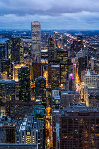 Illuminated modern buildings in city against sky at dusk