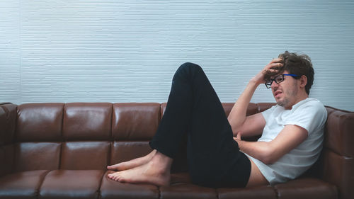 Man sitting on sofa against wall
