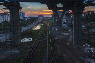 Railroad tracks in city against sky during sunset