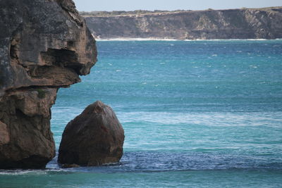 Rock formation by sea against sky