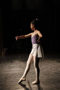 Full length of woman standing against black background