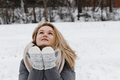 Portrait of smiling young woman standing on snow covered field