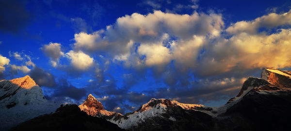 Low angle view of mountain range against cloudy sky 