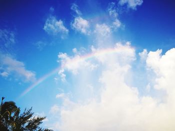 Low angle view of rainbow over blue sky